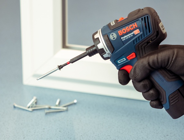 A cordless screw driver gun with self-drilling screws attached to driver bit.